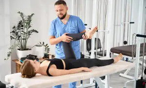 Fizjoterapeuta wykonuje test Thomasa, pomagając pacjentce w rehabilitacji.