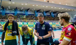 Trener Ireneusz Mazur udziela wskazówek siatkarzom w hali sportowej, wśród kibiców.