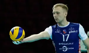 Siatkarz Mateusz Sacharewicz z piłką w dłoni, gotowy do zagrywki.