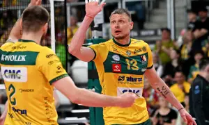 Jurij Gładyr, siatkarz w żółtej koszulce z numerem 13, unosi dłoń z białymi plastrami.