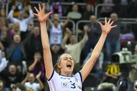 Karolina Drużkowska z uniesionymi rękami, krzyczy z radości na meczu siatkówki.
