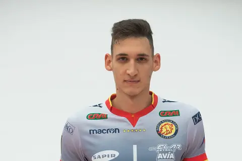 Młody siatkarz z krótką fryzurą, ubrany w szary strój z logo Porto Robur Costa Ravenna.