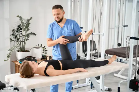 Fizjoterapeuta wykonuje test Thomasa, pomagając pacjentce w rehabilitacji.