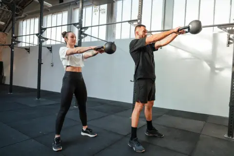 Para dowodowy na siłowni wykonuje ćwiczenie z kettlebell. To właśnie crossfit co to za trening?