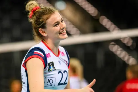 Uśmiechnięta siatkarka Natalia Lijewska w białej koszulce z numerem 22, z czerwoną opaską na włosach, podczas meczu.