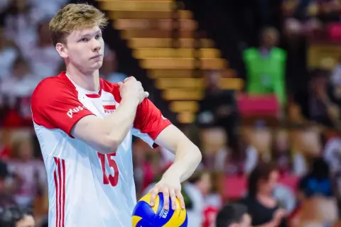 Młody siatkarz Jakub Kochanowski, numer 15, w biało-czerwonej koszulce reprezentacji Polski, z piłką w dłoni. Jego wzrost robi wrażenie.