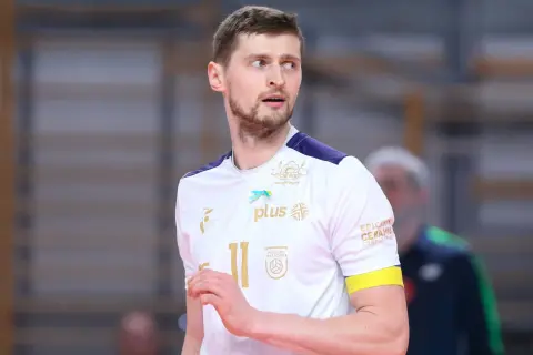 Piotr Nowakowski, siatkarz w białej koszulce z numerem 11, z uwagą obserwuje grę.