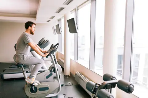Mężczyzna ćwiczy na rowerze stacjonarnym, który może być dobrym wyborem, jeśli zastanawiasz się, jaki rower stacjonarny do rehabilitacji kolana wybrać.