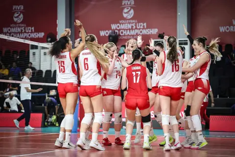 Drużyna siatkówki kobiet u21 świętuje zwycięstwo na Mistrzostwach Świata. Radość i entuzjazm po wygranej.
