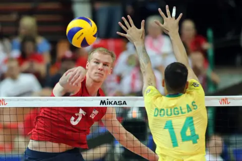 Kyle Russell z USA atakuje piłkę do siatkówki, blokowany przez Douglasa z Brazylii.