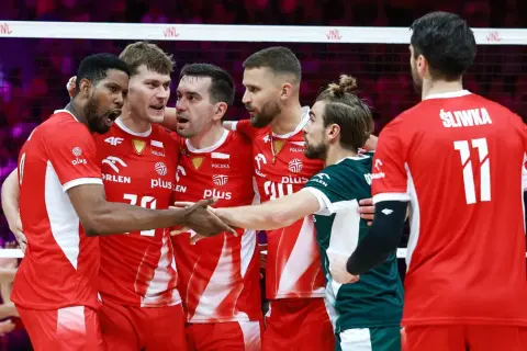 Drużyna Polski w siatkówce świętuje sukces w Lidze Narodów. Zawodnicy w czerwonych strojach z orłem na piersiach cieszą się po wygranej.