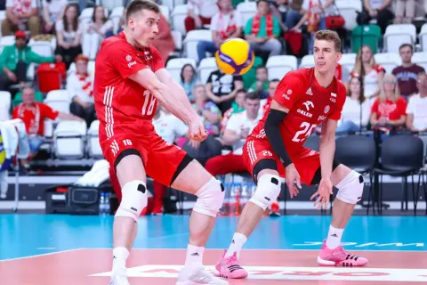 Dwóch siatkarzy w czerwonych strojach walczy o piłkę. Jeden z nich, numer 16, przyjmuje zagrywkę, drugi, numer 25, czeka na dalszy rozwój akcji. Zielona kartka w siatkówce nie istnieje, ale ta akcja jest warta złota!