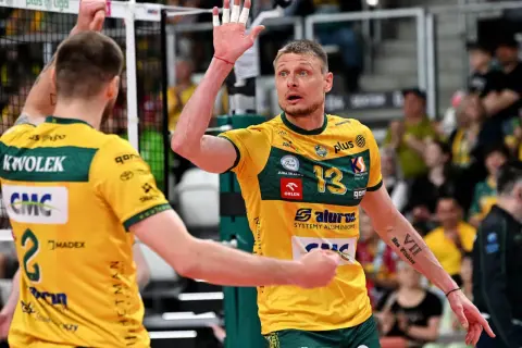 Jurij Gładyr, siatkarz w żółtej koszulce z numerem 13, unosi dłoń z białymi plastrami.