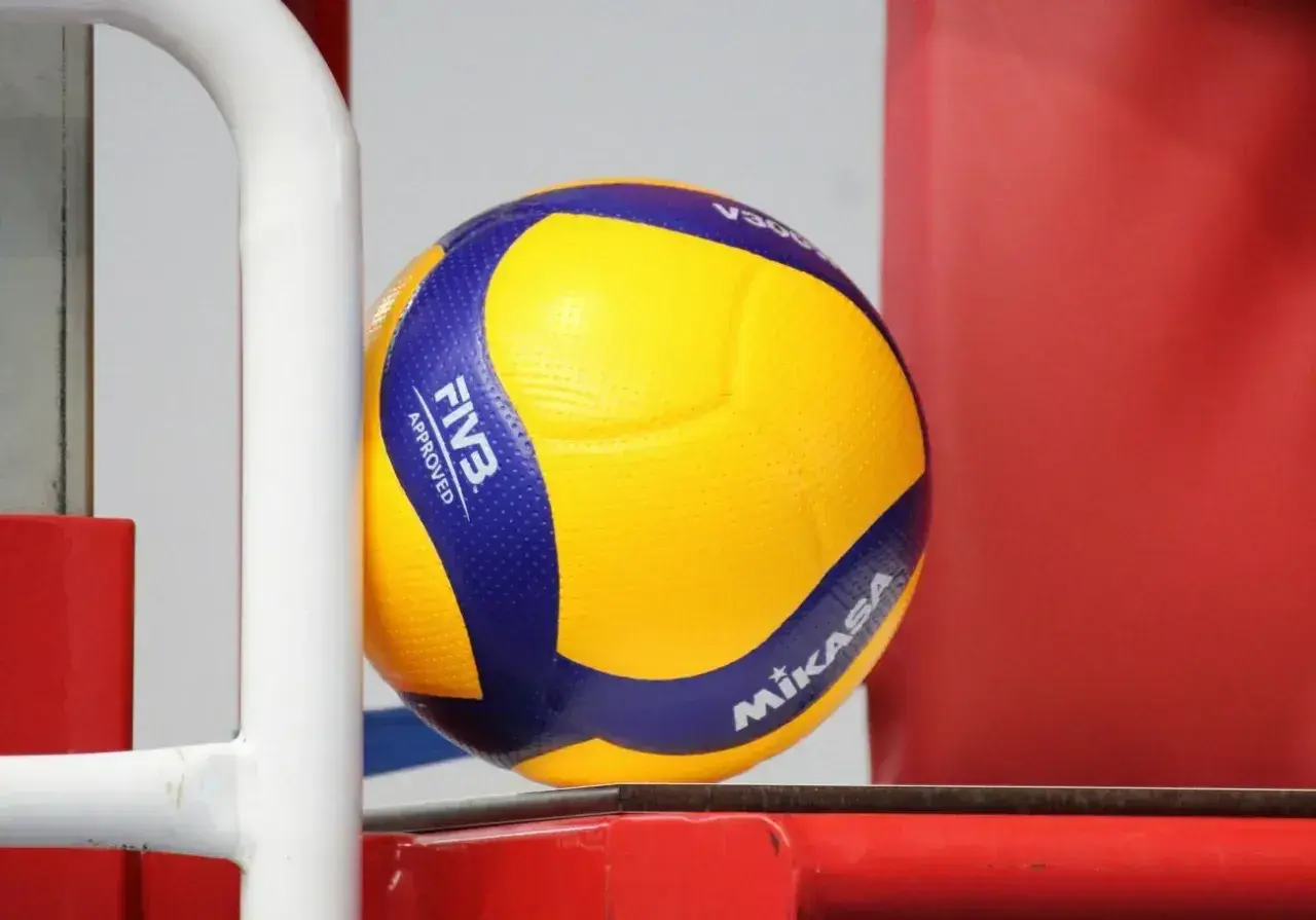 Żółta piłka do siatkówki Mikasa z niebieskimi pasami, z logo FIVB Approved.