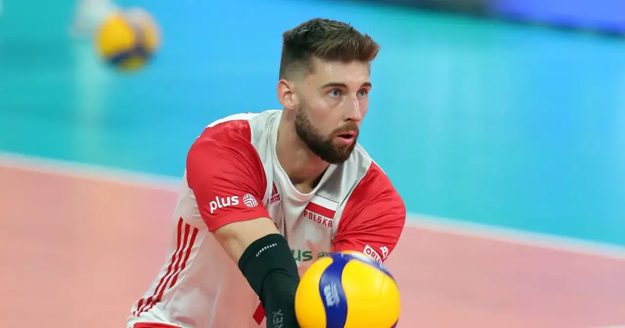 Bartek Bednorz w akcji, skupiony na zagraniu piłki siatkowej.