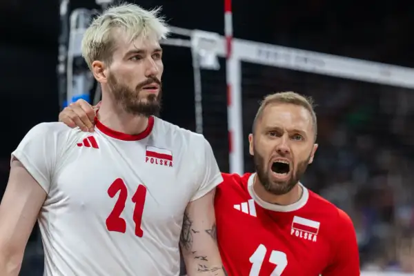 Paweł Zatorski, siatkarz w białej koszulce z numerem 21, otrzymuje wsparcie od kolegi z drużyny w czerwonej koszulce.