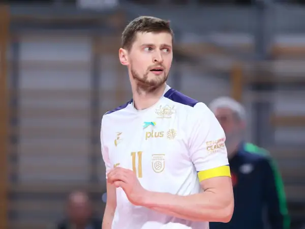 Piotr Nowakowski, siatkarz w białej koszulce z numerem 11, z uwagą obserwuje grę.